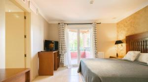 een slaapkamer met een bed, een tv en een raam bij Hotel Villa San Francisco in Marbella