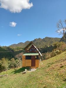 una pequeña cabaña en una colina con montañas en el fondo en casita en la montaña, cabañas paraíso, en Sesquilé