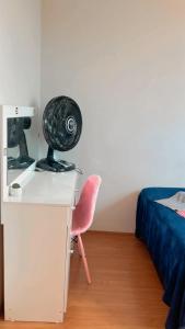 Cette chambre comprend un bureau avec un ventilateur et une chaise. dans l'établissement Apartamento ACOMODA 5 PESSOAS próximo ao Uberlândia Shopping, à Uberlândia