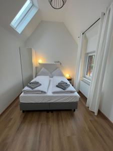a bedroom with a bed with white walls and wooden floors at Ostfriesenperle in Aurich