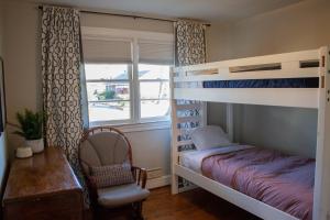 a bedroom with a bunk bed and a chair and a window at Beautiful Ranch Style Home - Minutes from Downtown CVille! in Charlottesville