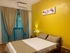 1 dormitorio con cama y pared amarilla en Tropical House en Pamandzi