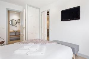 a white bedroom with a bed and a tv on a wall at Luderna - Apartamento con terraza Bonaigua B1 Joanchiquet in Baqueira-Beret