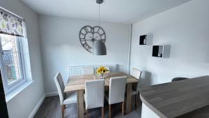 a dining room with a wooden table and white chairs at Tobar Oisinn in Oban