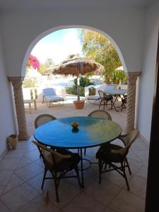 une terrasse avec une table bleue, des chaises et un parasol dans l'établissement Menzel Caja, à Aghir