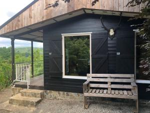 a black cabin with a bench and a window at Chalet hérisson in La Roche-en-Ardenne