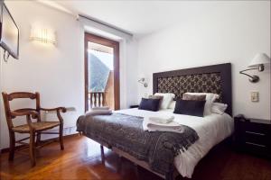 1 dormitorio con 1 cama con silla y ventana en Luderna - Apartamento con terraza Bonaigua B2 Salient, en Baqueira Beret