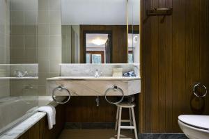 y baño con lavabo, bañera y taburete. en Luderna - Apartamento con terraza Bonaigua B2 Salient, en Baqueira Beret