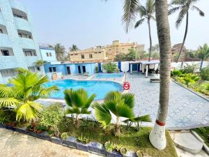 uma piscina com uma palmeira em frente a um edifício em Hotel V-i sea view, puri private-beach-gym-spa fully-airconditioned-hotel lift-and-parking-facilities breakfast-included em Puri