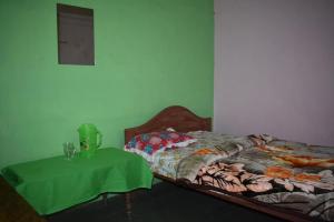 - une chambre avec un lit et une table verte dans l'établissement MANAS RAY HOMESTAY, à Jyoti Gaon