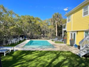 a swimming pool in a yard next to a yellow house at Nature View #3 in Fort Myers Beach