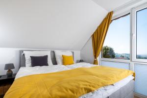 - une chambre avec un grand lit et une couverture jaune dans l'établissement Ferienhaus Mountain View Six53 mit Sauna und Kamin in St. Andreasberg, à Sankt-Andreasberg