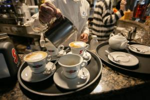 een persoon die koffie in twee kopjes giet op een aanrecht bij Albergo Italia in Porto Tolle