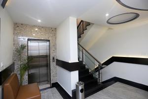a lobby with a staircase and a glass elevator at Collection O Hotel Pearl Blue in Tājganj