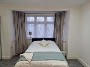 Schlafzimmer mit einem großen Bett und einem Fenster in der Unterkunft Elegant 2-Bedroom Double En-Suite Flat - London in Wanstead