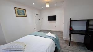 ein weißes Schlafzimmer mit einem Bett und einem Klavier in der Unterkunft Elegant 2-Bedroom Double En-Suite Flat - London in Wanstead