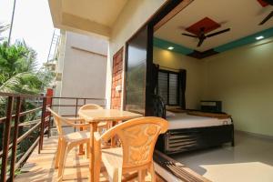 a balcony with a table and chairs and a bed at Redstone Resort-Nagaon-Alibaug in Nagaon