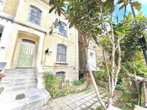 a brick house with a green door and a tree at Enticing 2 Bed 2 Bath Flat in Hackney with garden in London