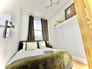 a bedroom with a bed with a green blanket at Enticing 2 Bed 2 Bath Flat in Hackney with garden in London