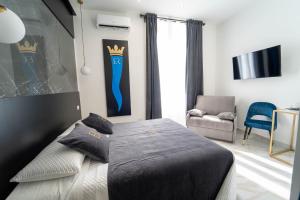 Schlafzimmer mit einem Bett, einem TV und einem Stuhl in der Unterkunft Élite Rooms in Neapel