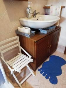 a bathroom with a sink and a chair next to a toilet at La casa di Silvia in Massarosa