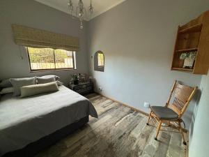 ein Schlafzimmer mit einem Bett, einem Stuhl und einem Fenster in der Unterkunft Stellenhaus Guest Cottage in Stellenbosch
