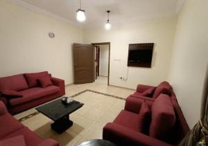 uma sala de estar com dois sofás vermelhos e uma televisão em فندق الافاق بالنسيم em Jeddah