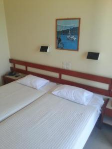 2 Betten in einem Schlafzimmer mit einem Bild an der Wand in der Unterkunft Hotel Avra in Ägina Stadt