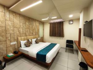 a hotel room with a bed and a flat screen tv at Hotel Kinara in Ahmedabad