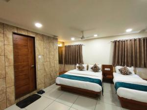 a hotel room with two beds and a door at Hotel Kinara in Ahmedabad