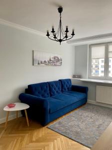 um sofá azul numa sala de estar com um lustre em Apartament 333 em Varsóvia