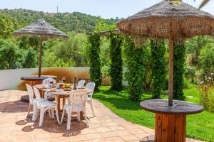 een patio met tafels, stoelen en parasols bij Countryside Retreat House in Monchique