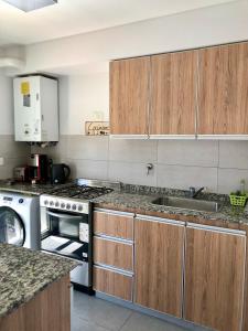 una cocina con fregadero y estufa horno superior en Comodo Monoambiente en puerto madryn, en Puerto Madryn