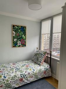華沙的住宿－Apartament 333，卧室配有一张床,墙上挂有绘画作品