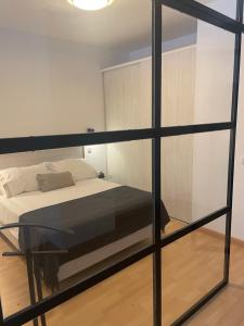 1 dormitorio con 1 cama y pared de cristal en Soho Moraleja I, en Alcobendas