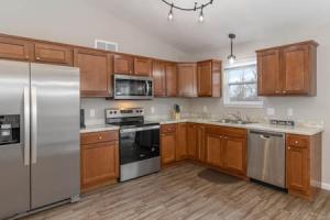 a kitchen with wooden cabinets and stainless steel appliances at BRAND NEW Home away from Home among the Nook in Hamilton