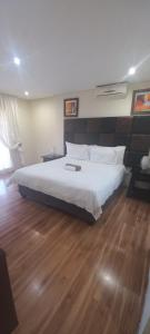 a bedroom with a large white bed and wooden floors at Cavilla Lodge in Vereeniging