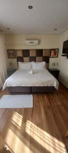 a bedroom with a large white bed with a wooden floor at Cavilla Lodge in Vereeniging