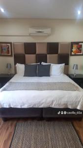 a bedroom with a large bed with a large headboard at Cavilla Lodge in Vereeniging