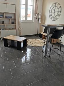 een kamer met een tegelvloer, een tafel en een klok bij Studio centre historique vue Mer in Sainte-Maxime