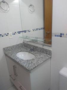 ein Bad mit einem Waschbecken und einem Spiegel in der Unterkunft #Apto a beira-mar na Praia do Sul de Ilhéus in Ilhéus