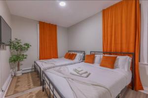 deux lits dans une chambre avec des rideaux orange dans l'établissement 40 OFF 3Days, 9 min to EWR, 2 Queen Beds, Sleeps 6, à Newark 19 autres photos