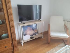 a flat screen tv sitting on a stand with a chair at Apartamento frente al Kursaal y la playa in Donostia-San Sebastián