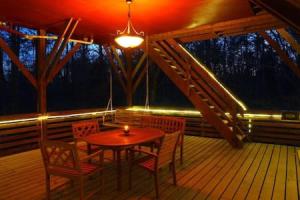 a wooden porch with a table and chairs on a deck at Treehouse at Castle in Stanardsville