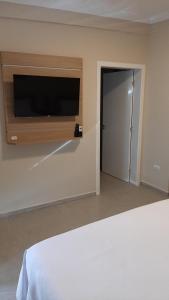 1 dormitorio con TV de pantalla plana en la pared en Farol das Aguas en Igaratá