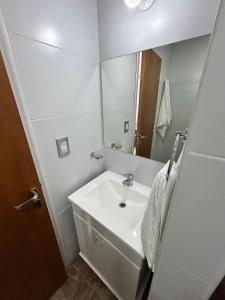 een witte badkamer met een wastafel en een spiegel bij Plaza Km 325 in San Lorenzo