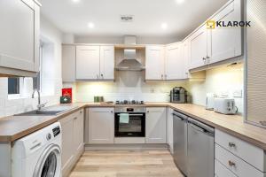 a kitchen with white cabinets and a washer and dryer at 30% OFF 28 Nights+ 3bed House - Klarok - Peterborough in Peterborough