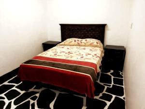 a bedroom with a bed with a black and white comforter at La cabaña del TIO PEPE in Taxco de Alarcón