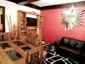 a living room with a red wall and a black couch at La cabaña del TIO PEPE in Taxco de Alarcón