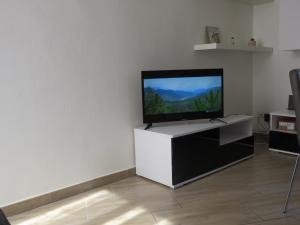 a flat screen tv on a white stand in a living room at Casa Luna tra Como e Milano in Saronno